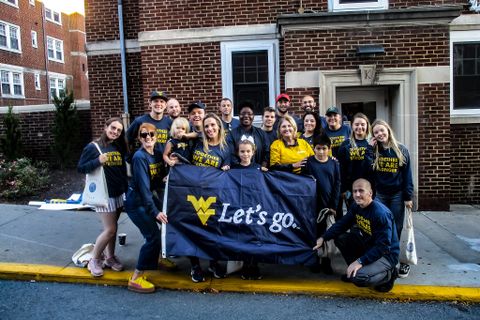 collegiate recovery members posing for photo with the WVU let's go flag